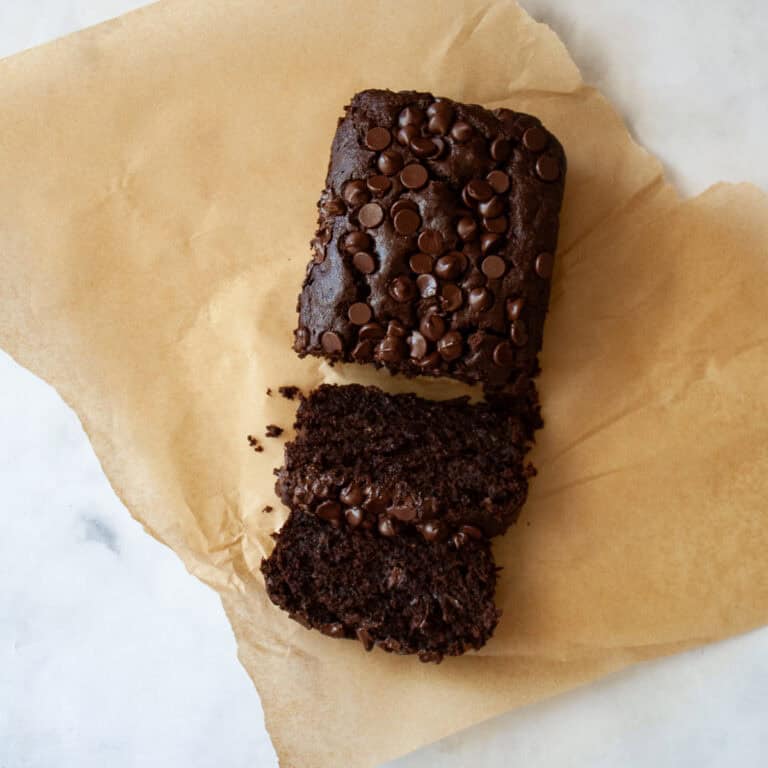 A sliced loaf of double chocolate banana bread on a piece of parchment paper.