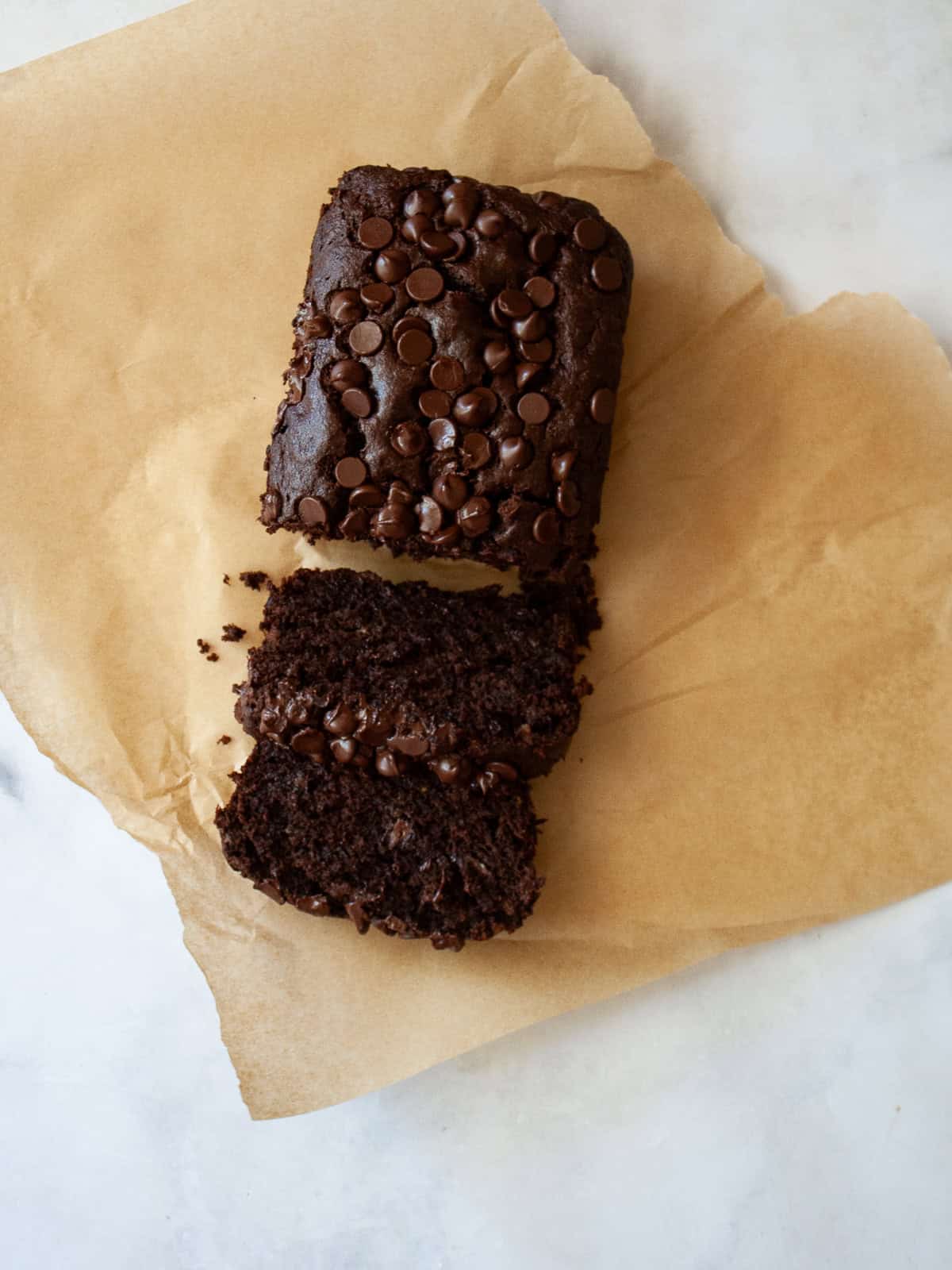 A sliced loaf of double chocolate banana bread on a piece of parchment paper.