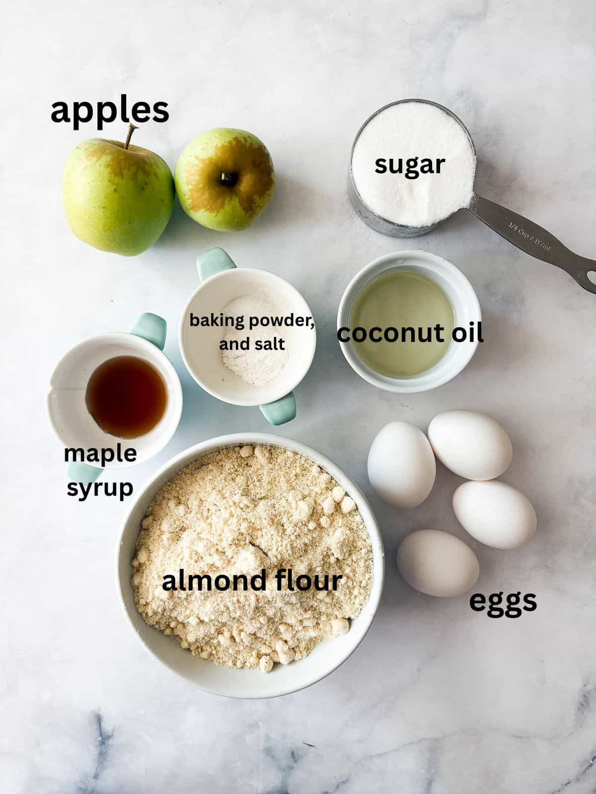 This rich-tasting almond flour apple cake has a wonderfully moist and tender crumb that's topped with sliced apples and maple syrup. Ingredients for almond flour apple cake are text-labeled.