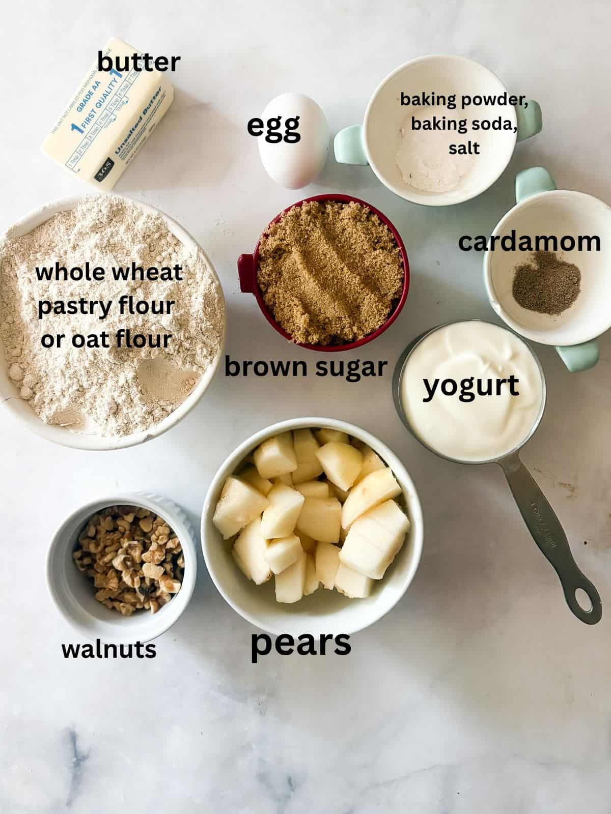 Loaded with fresh, juicy pears, these whole grain pear muffins are studded with walnuts and finished with a crunchy cap of brown sugar. Ingredients for pear muffins are text-labeled.