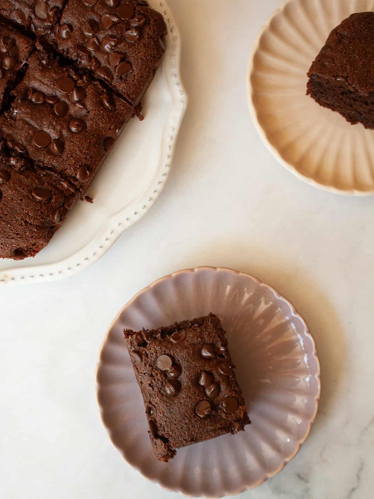 This irresistible one bowl almond flour chocolate cake is wonderfully fluffy and rich, and you need just one simple flour to make it. An almond flour chocolate cake on a plate with slices of cake next to it.