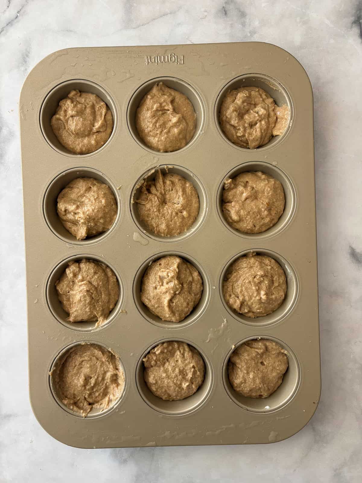 Simple and wholesome, these whole grain applesauce muffins are packed with unsweetened applesauce. Easy to make gluten-free, dairy-free, etc. Applesauce muffins batter in a muffin tin.