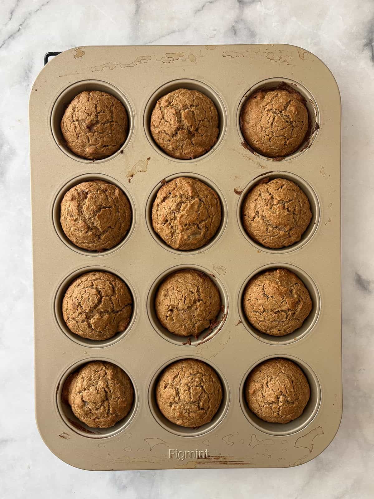 Simple and wholesome, these whole grain applesauce muffins are packed with unsweetened applesauce. Easy to make gluten-free, dairy-free, etc. A muffin tin full of baked applesauce muffins.