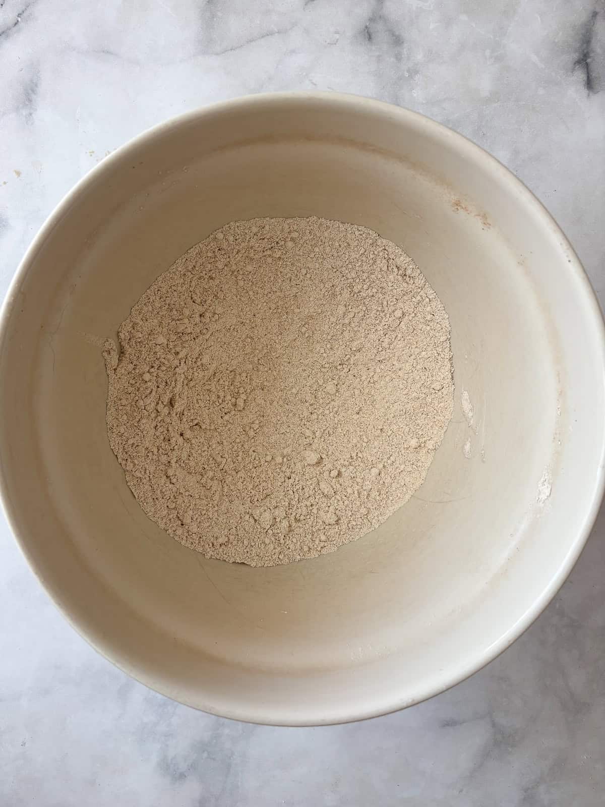 Simple and wholesome, these whole grain applesauce muffins are packed with unsweetened applesauce. Easy to make gluten-free, dairy-free, etc. Dry ingredients are combined in a bowl for applesauce muffins.