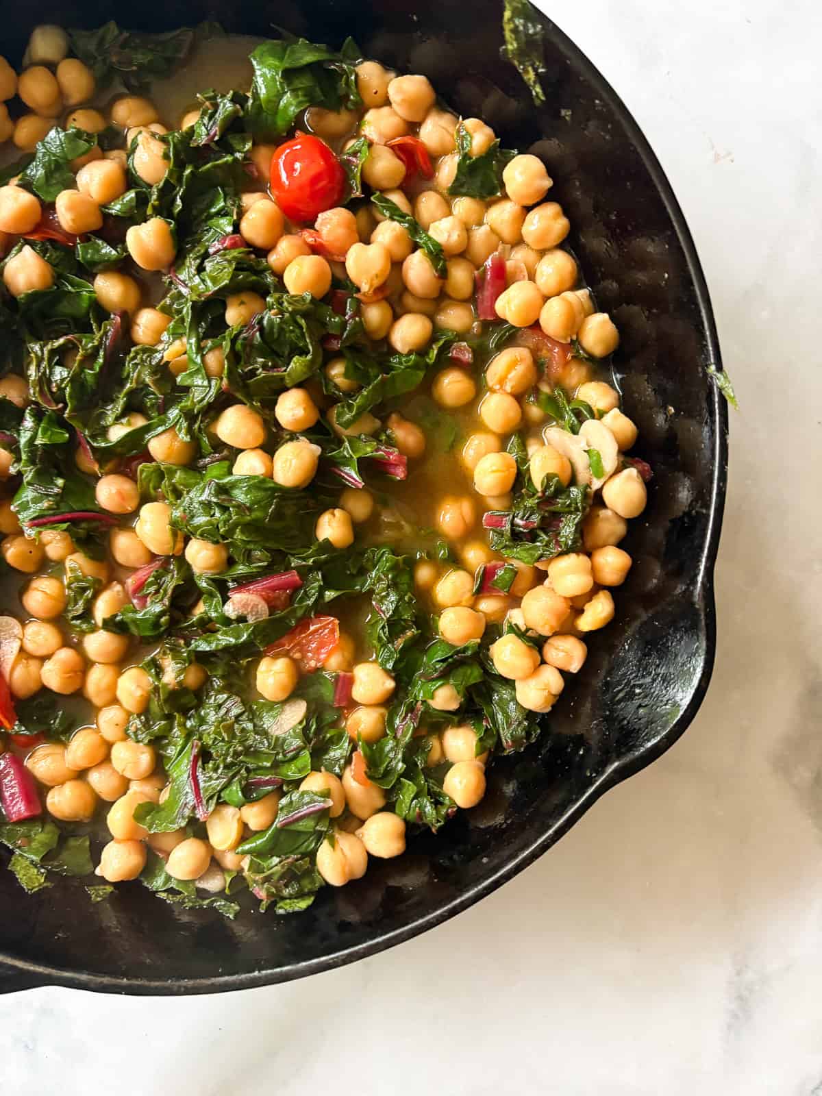 This easy beans and greens recipe comes together in minutes with pantry beans and fresh greens. A simple, adaptable weeknight meal. A skillet of beans and greens.