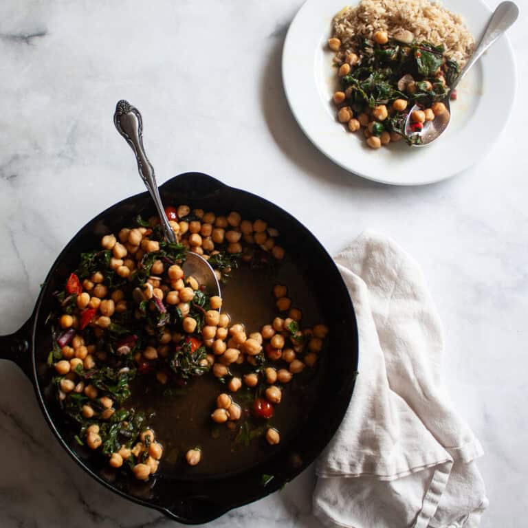 A cast iron skillet of beans and greens and a plate of beans and greens.