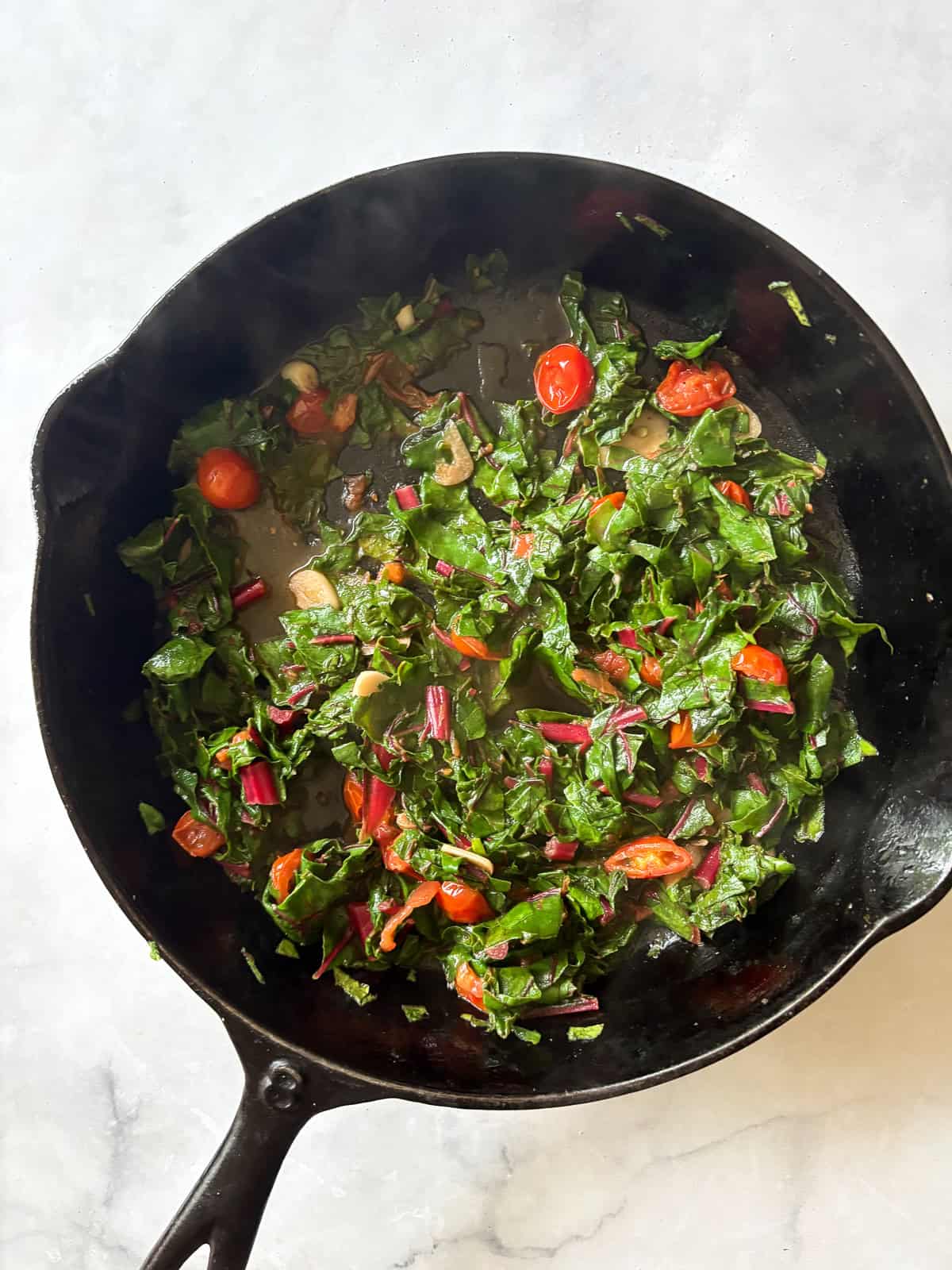 This easy beans and greens recipe comes together in minutes with pantry beans and fresh greens. A simple, adaptable weeknight meal. Greens added to a skillet for beans and greens.