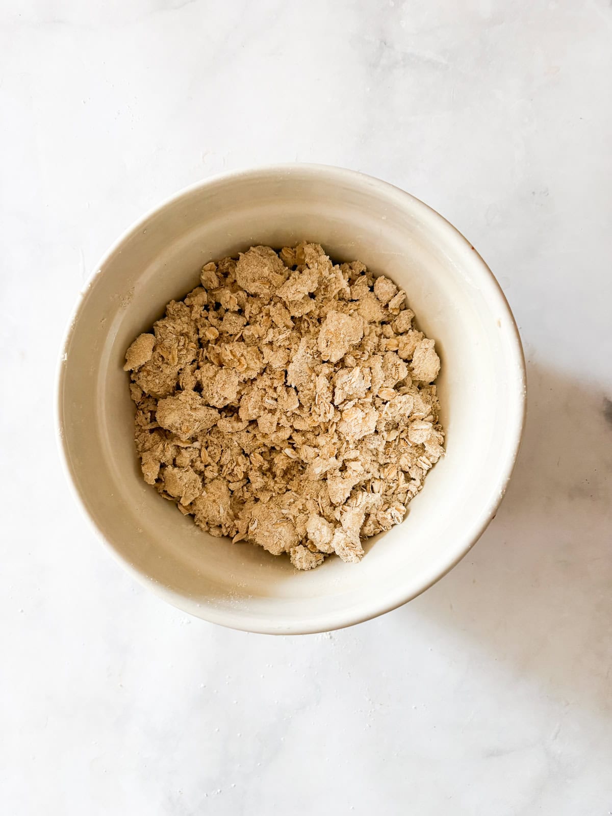 This apple blueberry crisp combines juicy summer apples and berries under a buttery oat topping. A seasonal dessert that's delicious warm. Topping for apple blueberry crisp is mixed in a bowl.