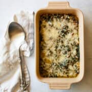 A serving spoon rests on a napkin next to a dish of chard gratin.