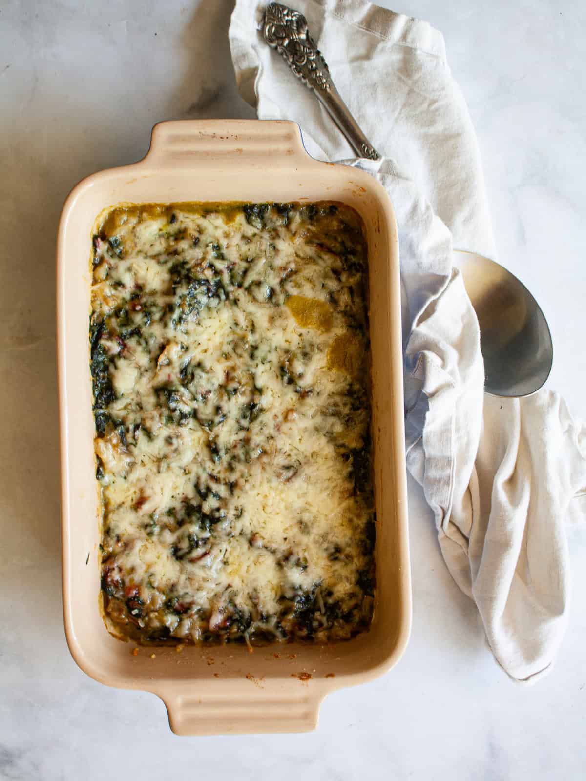 A white napkin alongside a baking dish of chard gratin.