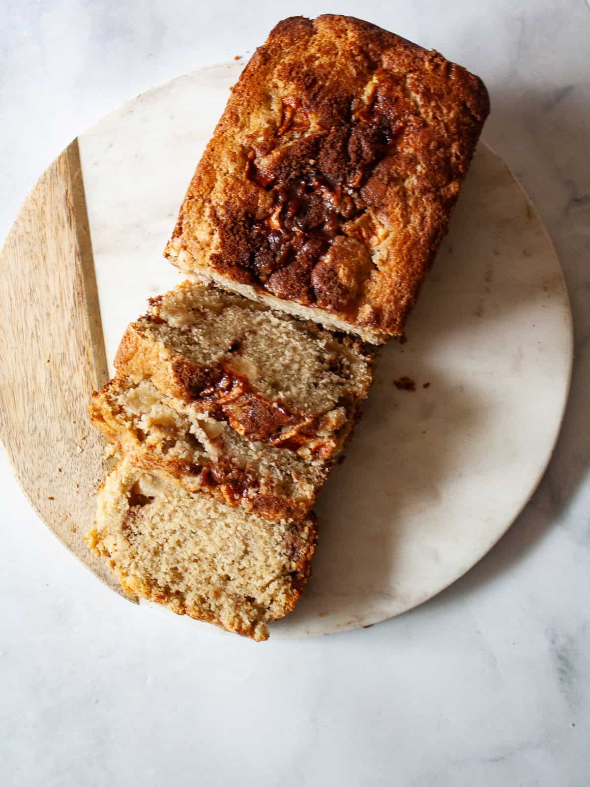 A loaf of gluten free apple bread on a cutting board cut into slices.