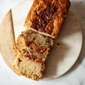 A loaf of gluten free apple bread on a cutting board cut into slices.