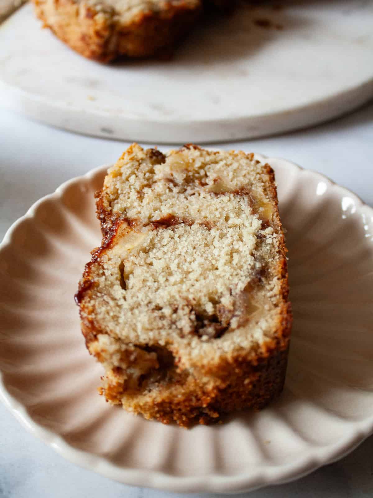 This gluten free apple bread is soft, buttery, and generously layered with fresh apples, cinnamon, and brown sugar. A one-bowl recipe! A slice of cinnamon-swirled gluten free apple bread on a plate.