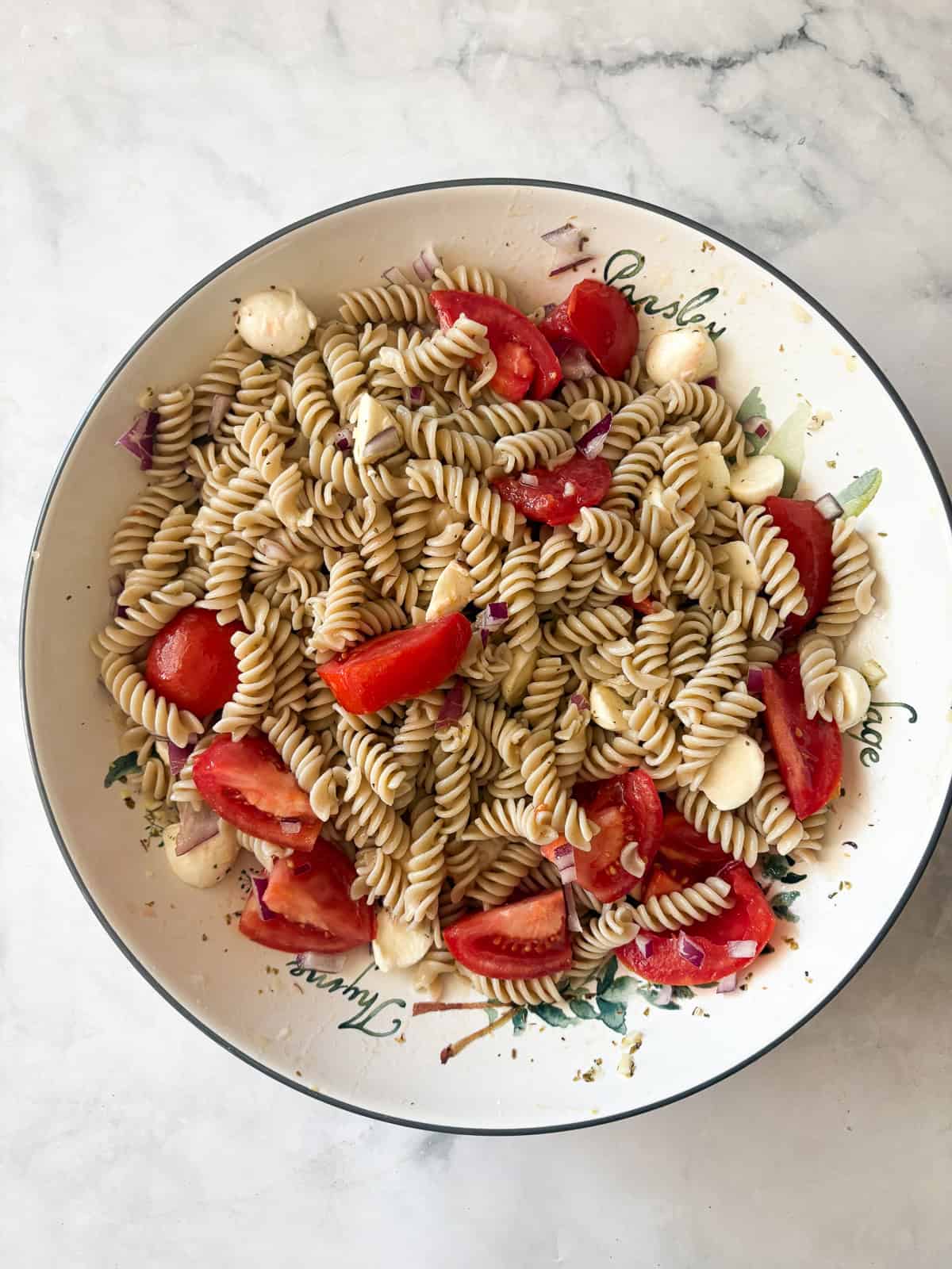 A summer staple, my gluten free pasta salad recipe features a zingy lemon dressing, fresh mozzarella, tomatoes, and fresh herbs. Vegetables and cheese are added to gluten free pasta salad.