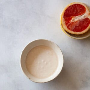 Grapefruit glaze in a bowl with a half of a grapefruit next to it.