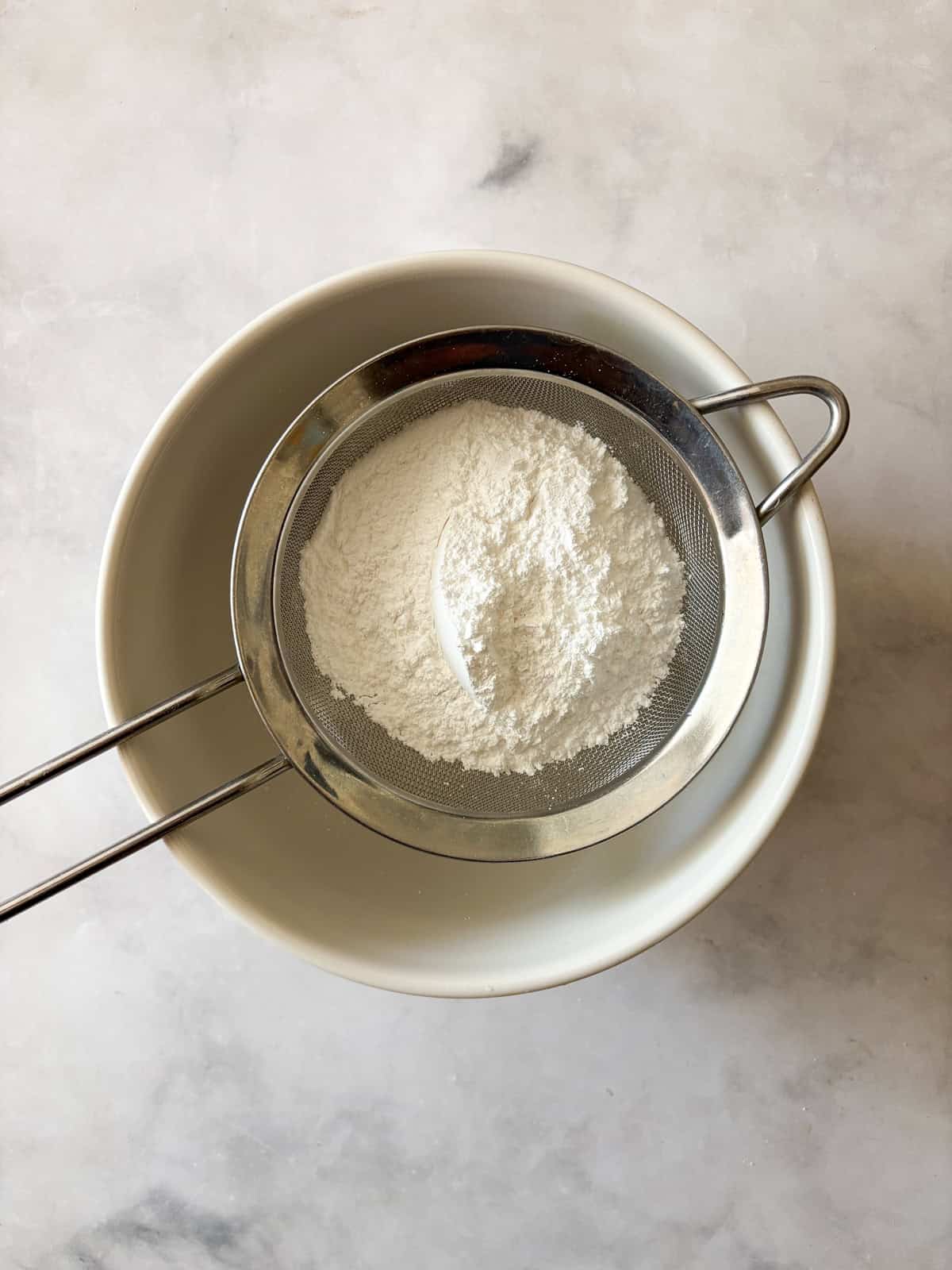 This two-ingredient orange glaze adds sweet citrus flavor to cakes, quick breads, scones, muffins, and more! Powdered sugar sifted into a bowl for grapefruit glaze.
