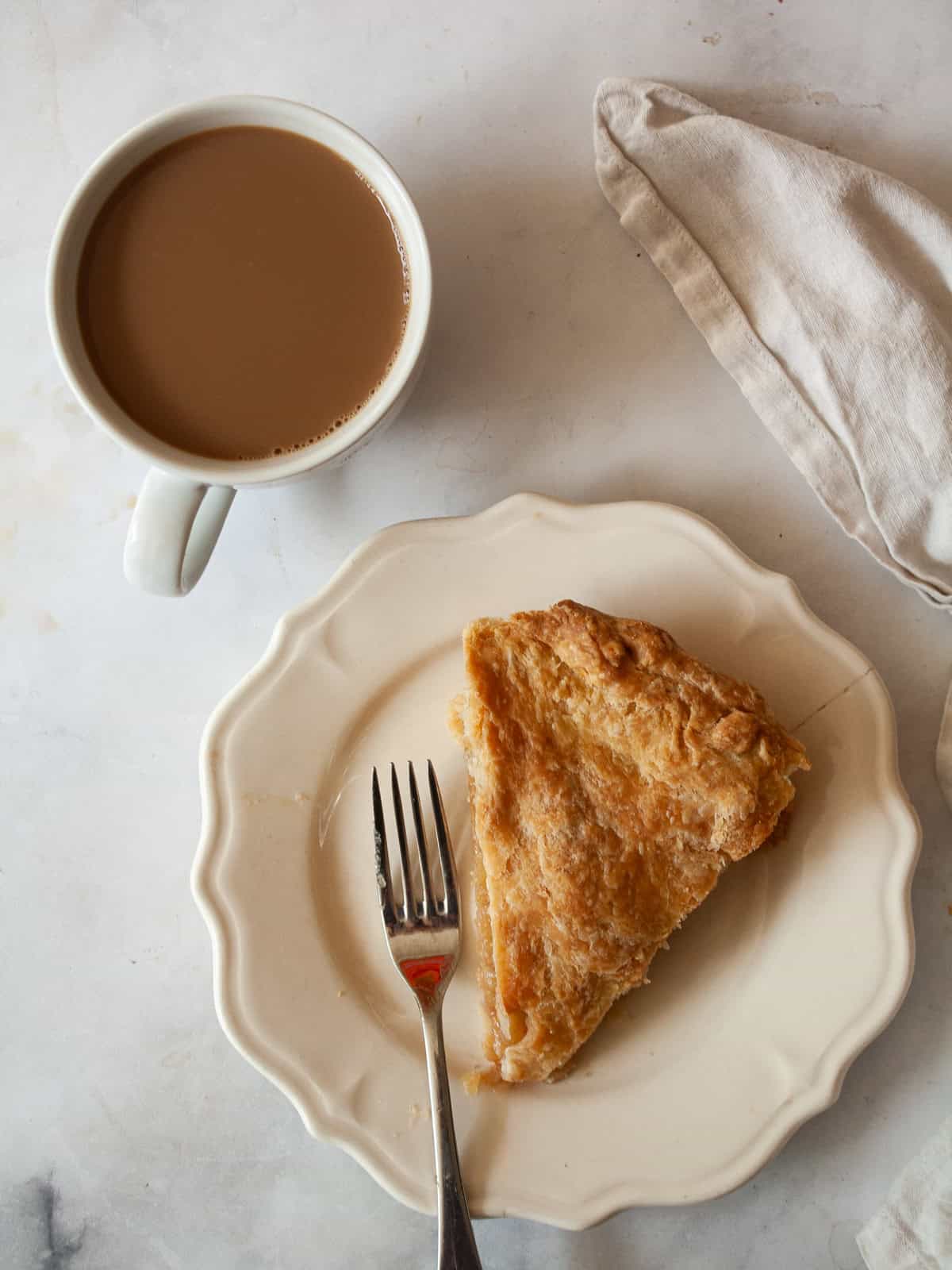 Delicious Gravenstein Apple Pie makes the most of the apple's short season. Make this pie when Gravs are in season - you won't regret it! A slice of Gravenstein apple pie on a plate with a fork and cup of coffee.
