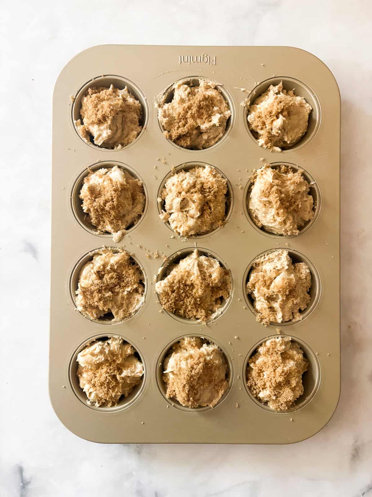 Loaded with fresh, juicy pears, these whole grain pear muffins are studded with walnuts and finished with a crunchy cap of brown sugar. Brown sugar is sprinkled over pear muffins in a baking tin.