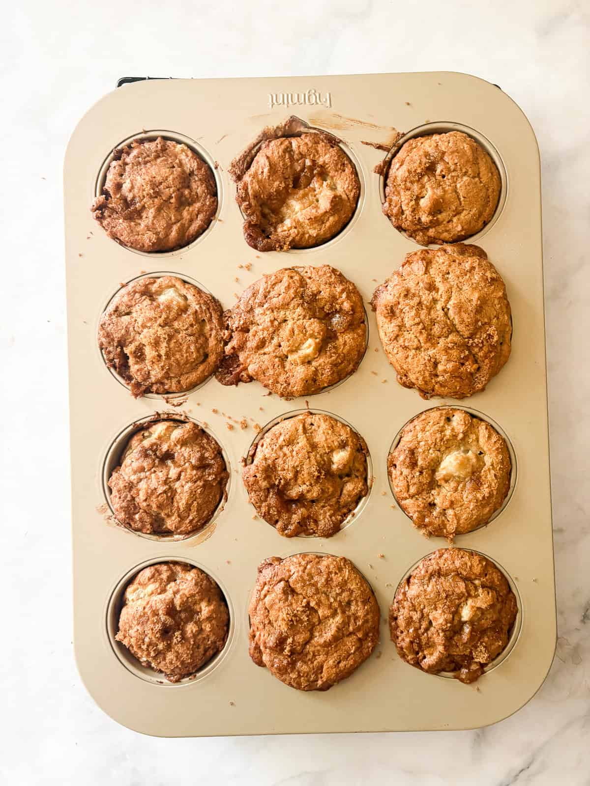 Loaded with fresh, juicy pears, these whole grain pear muffins are studded with walnuts and finished with a crunchy cap of brown sugar. A baked tin of pear muffins.