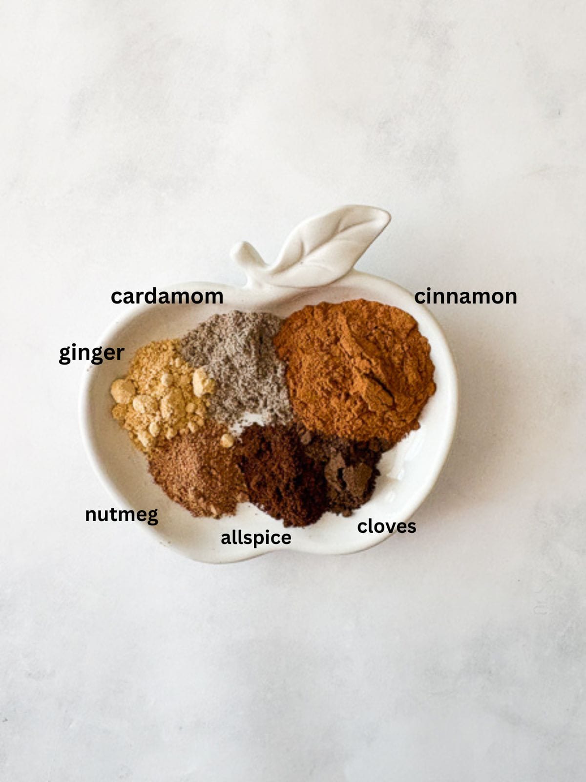 Make easy homemade apple pie spice with cinnamon, nutmeg, ginger, allspice, cloves, and cardamom. Perfect for fall baking! Apple pie spice recipe ingredients are text-labeled.