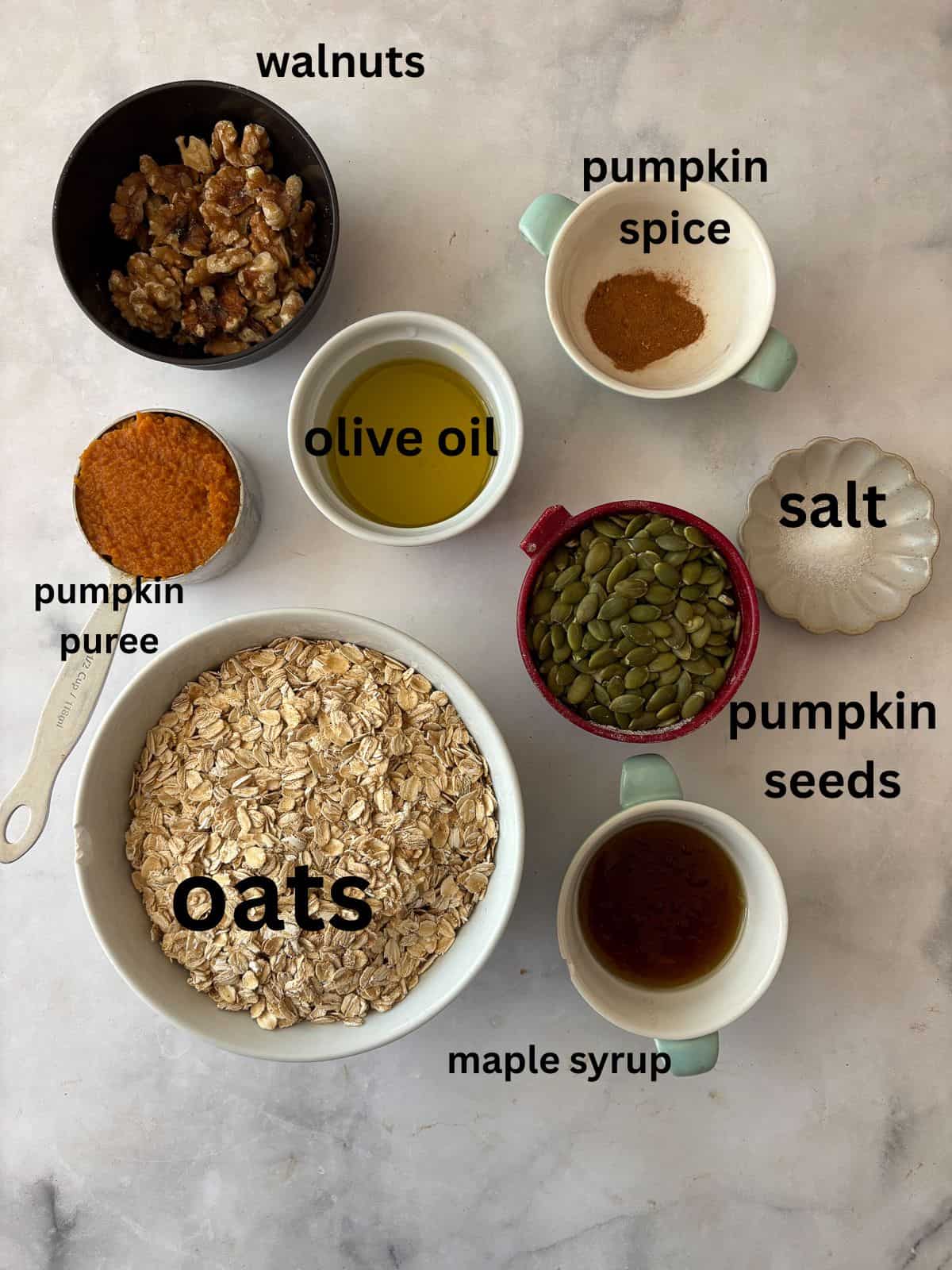 Enjoy this pumpkin spice granola that's made with pumpkin puree, warm spices, crunchy walnuts and pumpkin seeds, olive oil, and maple syrup. Ingredients for pumpkin spice granola are text-labeled.