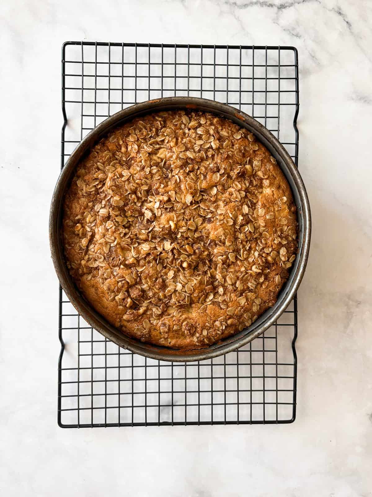 This delicious apple crumb cake is layered with apples, cinnamon, oats, and walnuts. Make it with whole wheat or oat flour for a GF version. An apple crumb cake cools in the pan.