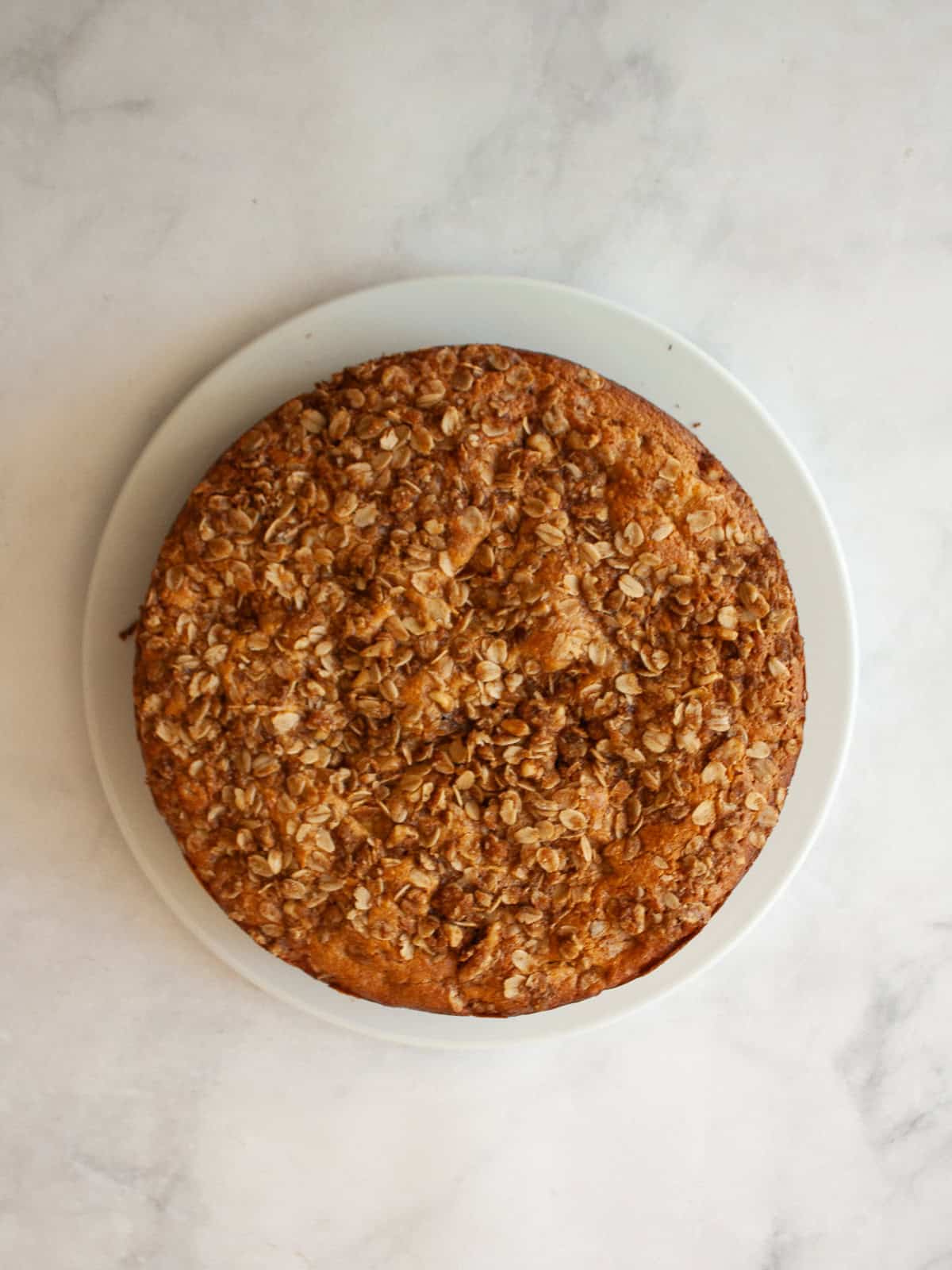 This delicious apple crumb cake is layered with apples, cinnamon, oats, and walnuts. Make it with whole wheat or oat flour for a GF version. An apple crumb cake on a plate.