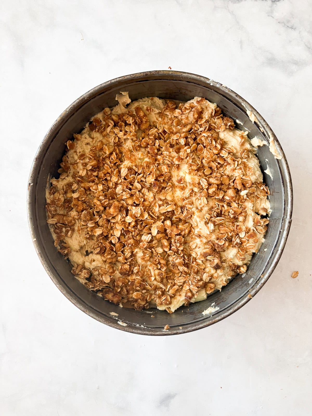 Assembling the apple crumb cake in a pan.