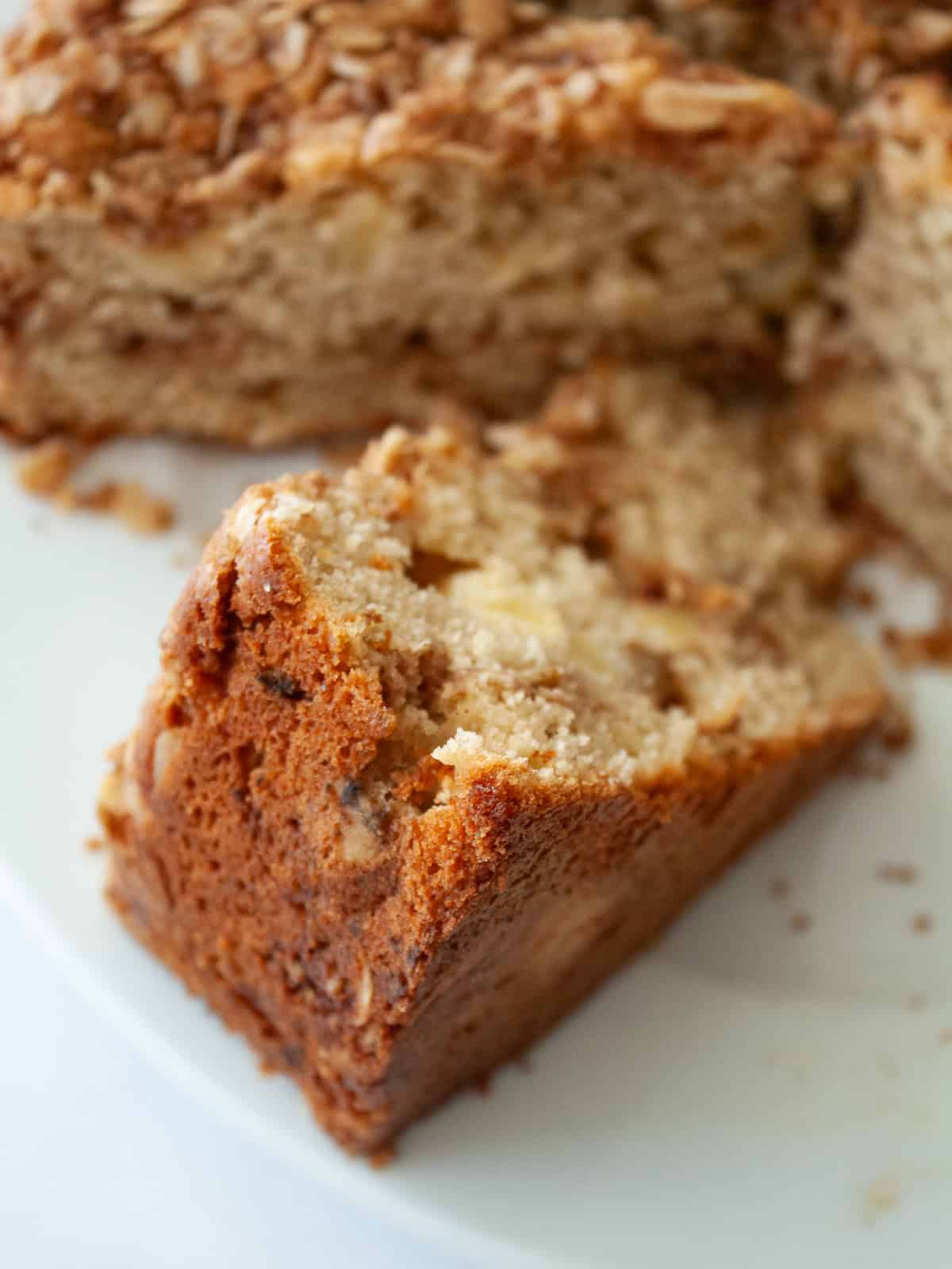 This delicious apple crumb cake is layered with apples, cinnamon, oats, and walnuts. Make it with whole wheat or oat flour for a GF version. A slice of apple crumb cake on a plate.