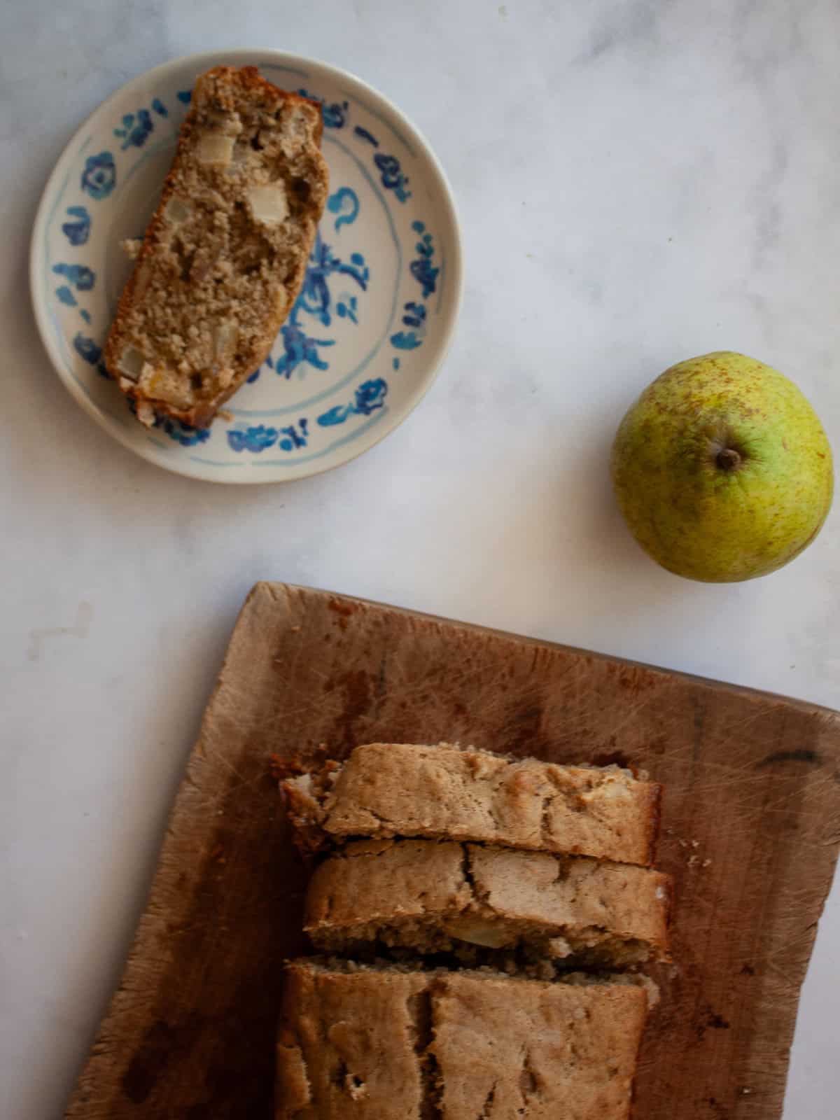 Easy banana pear bread made with whole wheat or gluten-free oat flour, juicy pears, and walnuts. A tender quick bread for fall and beyond. A pear, a slice of banana pear bread, and a loaf of bread.