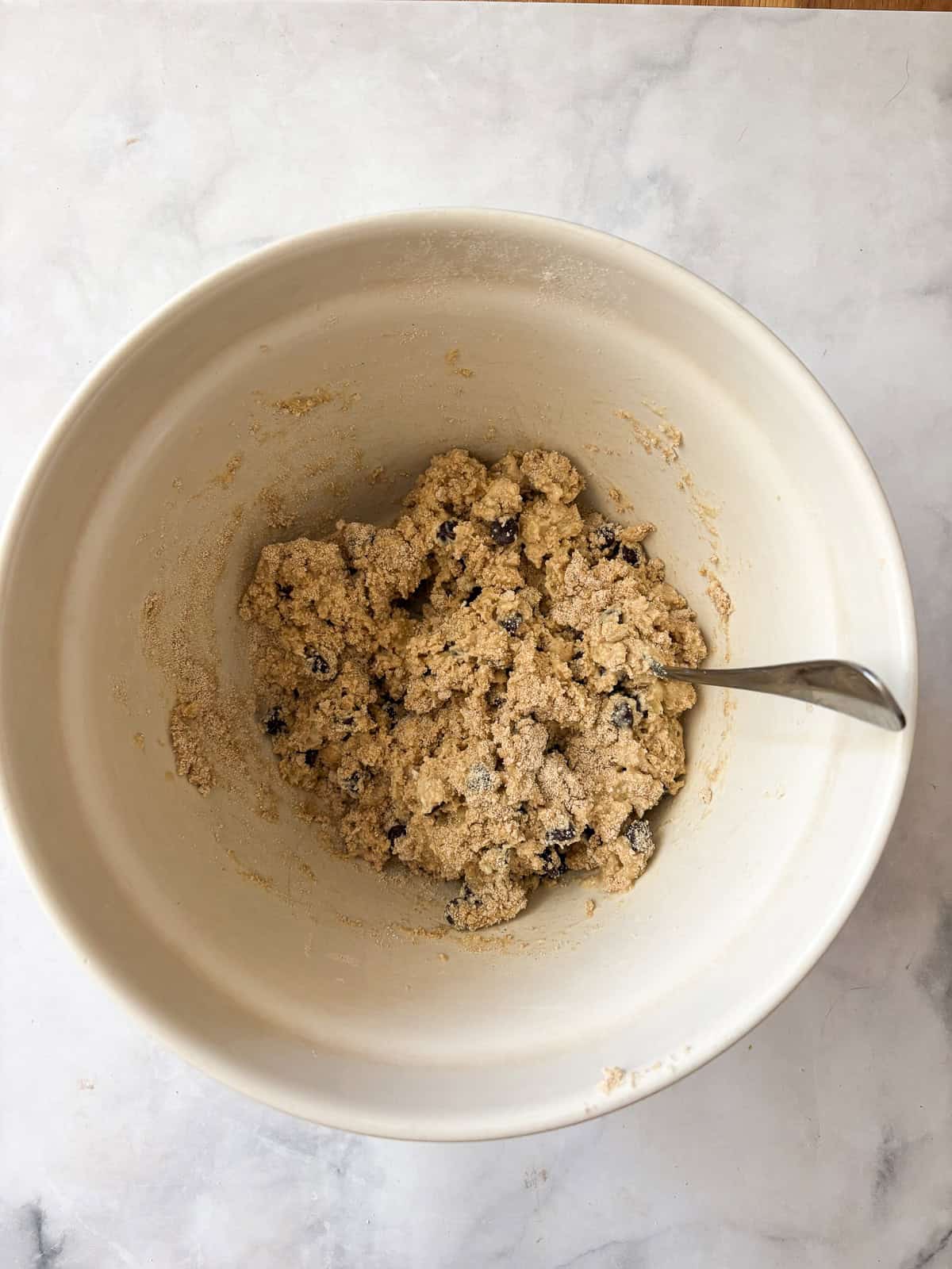 These whole grain banana scones are filled with chocolate chips, cinnamon, and a whole ripe banana for a tender, lightly sweet treat. Mixing the dough for banana scones in a bowl.