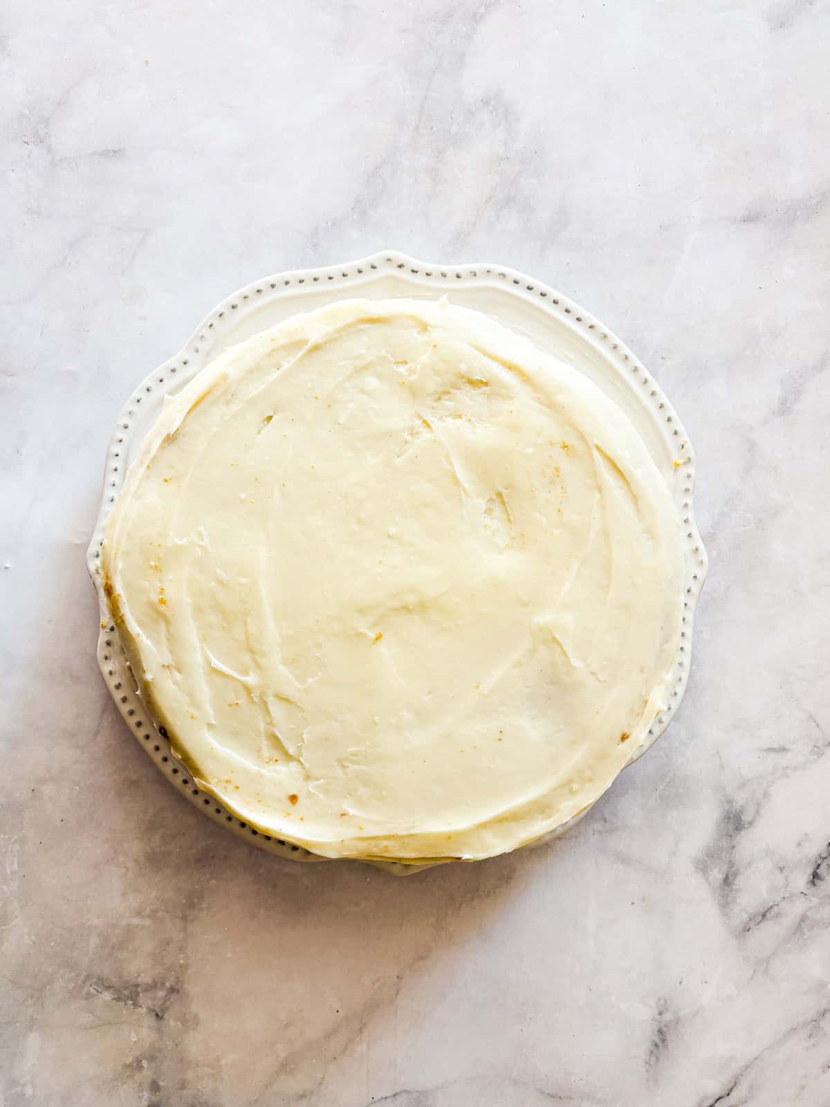 This beautiful gluten free pumpkin layer cake is rich and moist, warmly spiced, and frosted with a plush, sweet-tangy cream cheese frosting. A gluten free pumpkin layer cake on a plate on a counter.