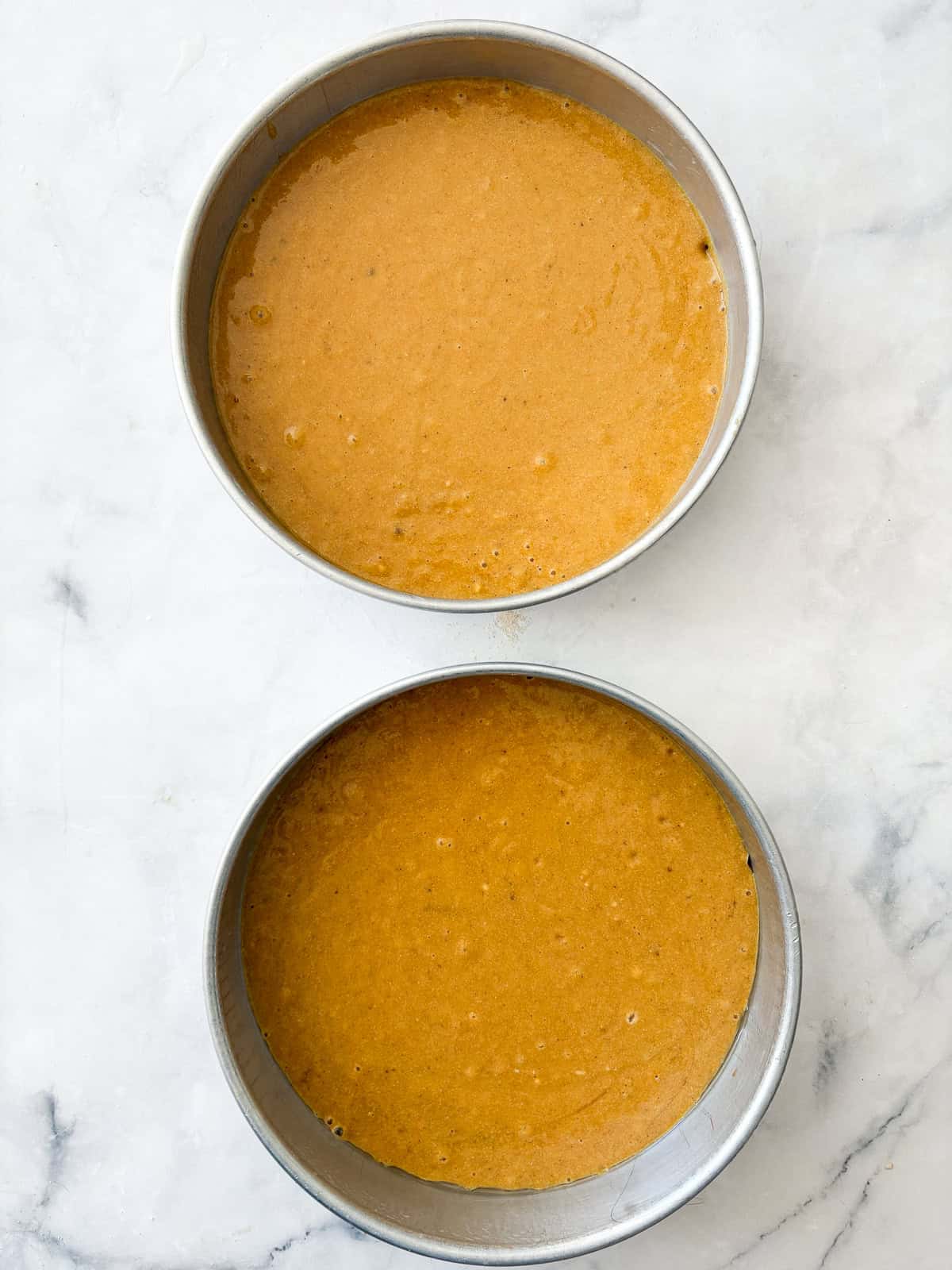 This beautiful gluten free pumpkin layer cake is rich and moist, warmly spiced, and frosted with a plush, sweet-tangy cream cheese frosting. Gluten free pumpkin layer cake batter in a 2 cake pans.