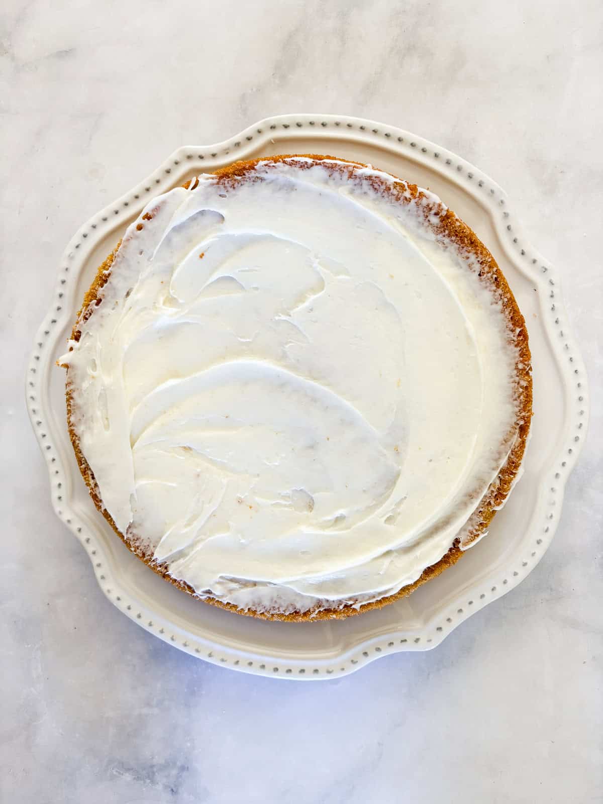 This beautiful gluten free pumpkin layer cake is rich and moist, warmly spiced, and frosted with a plush, sweet-tangy cream cheese frosting. Frosting is added to a gluten free pumpkin layer cake.