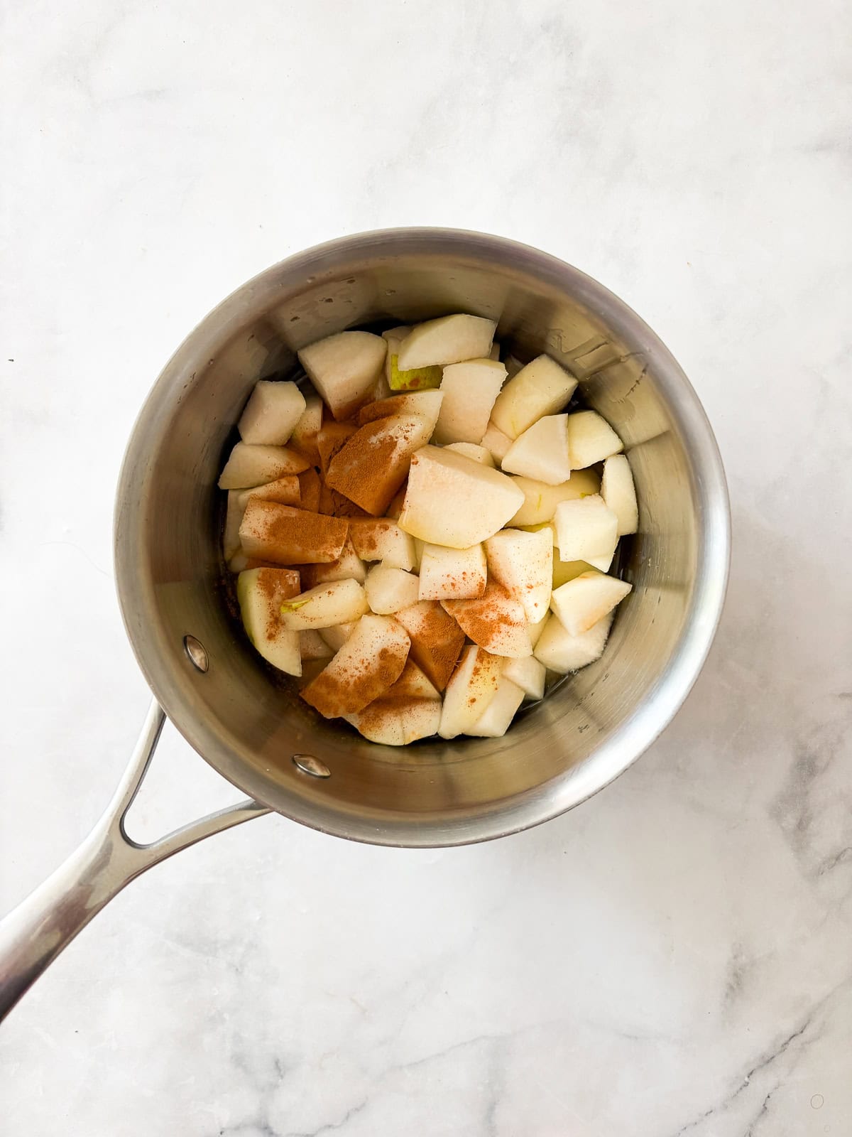A smooth, sweet pear sauce that's best made with ripe pears! Add cinnamon and maple syrup if you like, or enjoy it plain. Adding cinnamon and maple syrup to pears in a pot for pear sauce.