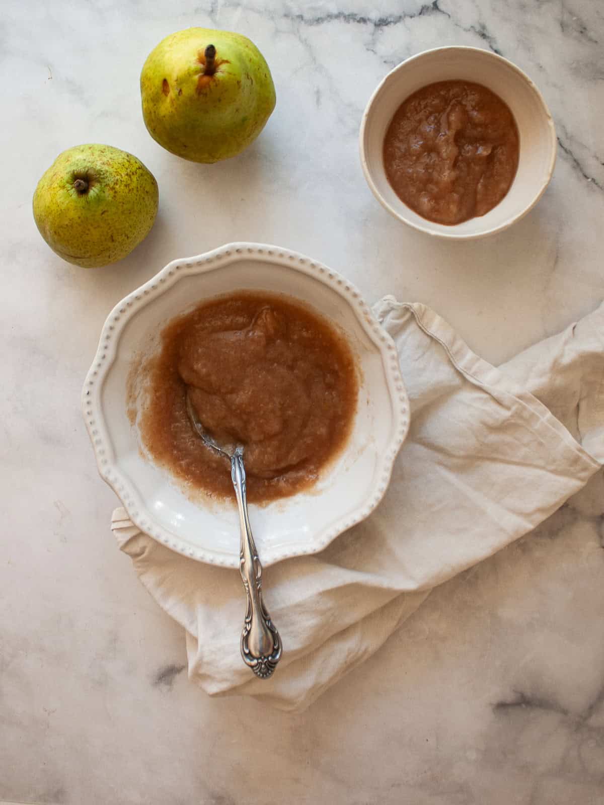 A smooth, sweet pear sauce that's best made with ripe pears! Add cinnamon and maple syrup if you like, or enjoy it plain. A small bowl of pear sauce next to a large bowl of pear sauce and 2 pears.