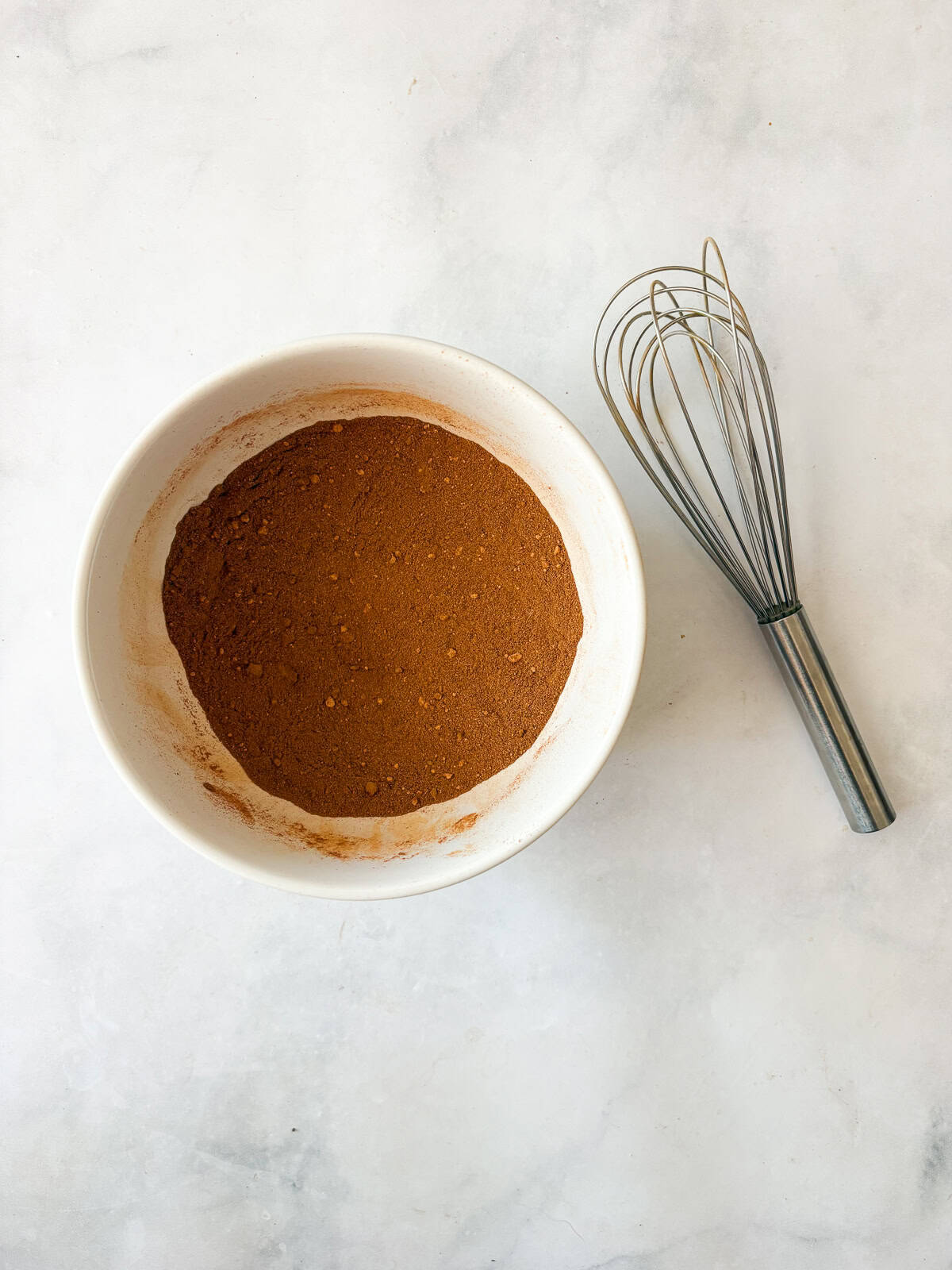 A homemade, versatile pumpkin spice blend with cinnamon, nutmeg, ginger, cloves, and allspice. Great in pies, muffins, quick breads, and more! Spices are whisked together in a bowl for homemade pumpkin spice blend.