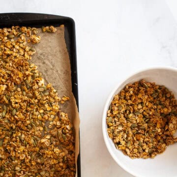 A tray of pumpkin spice granola next to a bowl of granola.