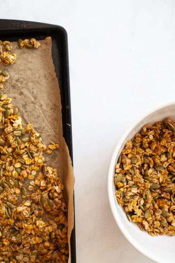 A tray of pumpkin spice granola next to a bowl of granola.