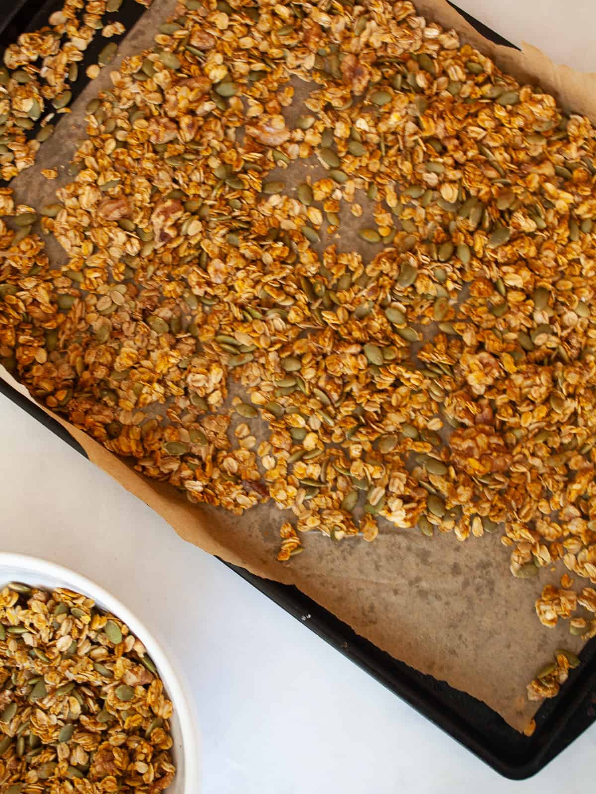 Enjoy this pumpkin spice granola that's made with pumpkin puree, warm spices, crunchy walnuts and pumpkin seeds, olive oil, and maple syrup. A tray of baked pumpkin spice granola.