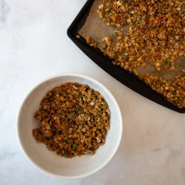 A bowl of pumpkin spice granola and a tray of granola.