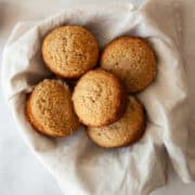 A bowl of spice muffins with a white napkin.